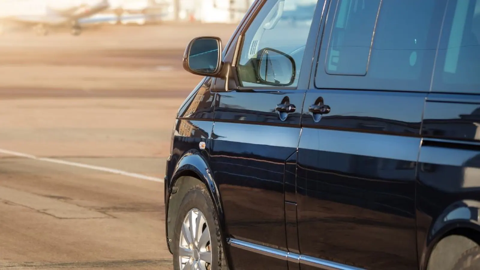 A black passenger van parked in the sun