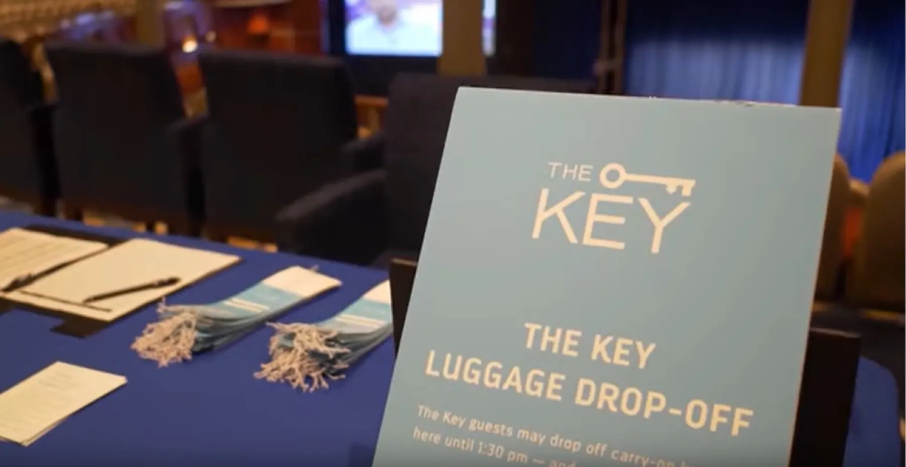 The Key luggage drop-off sign on a table