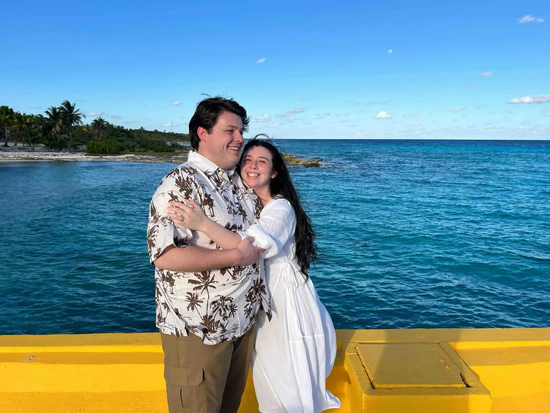 A couple on the deck with the sea behind them